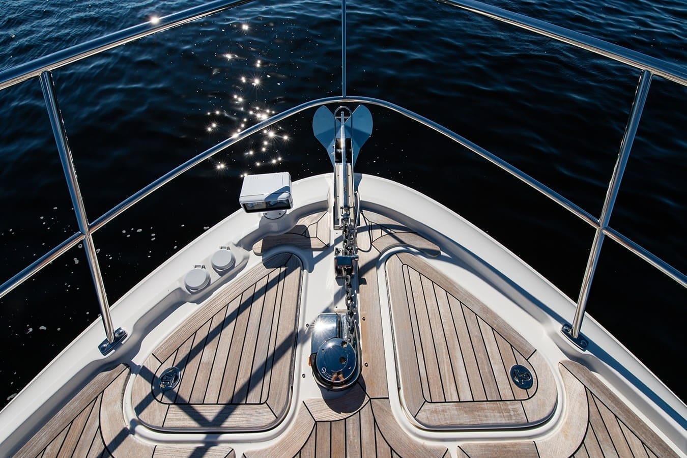 Anchor and chain at the bow over dark sparkling water