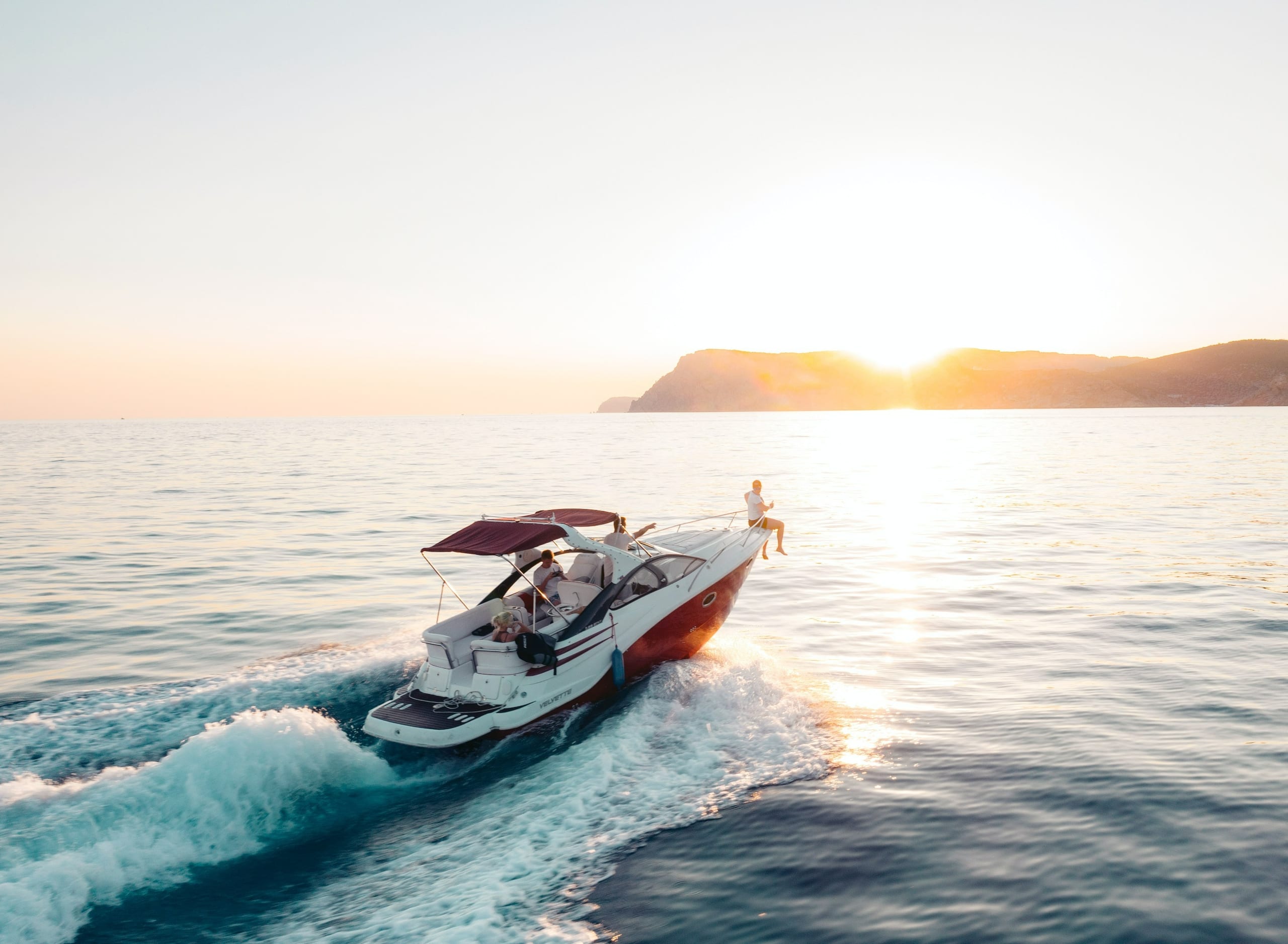 A motor yacht running toward the sunset along the coastline