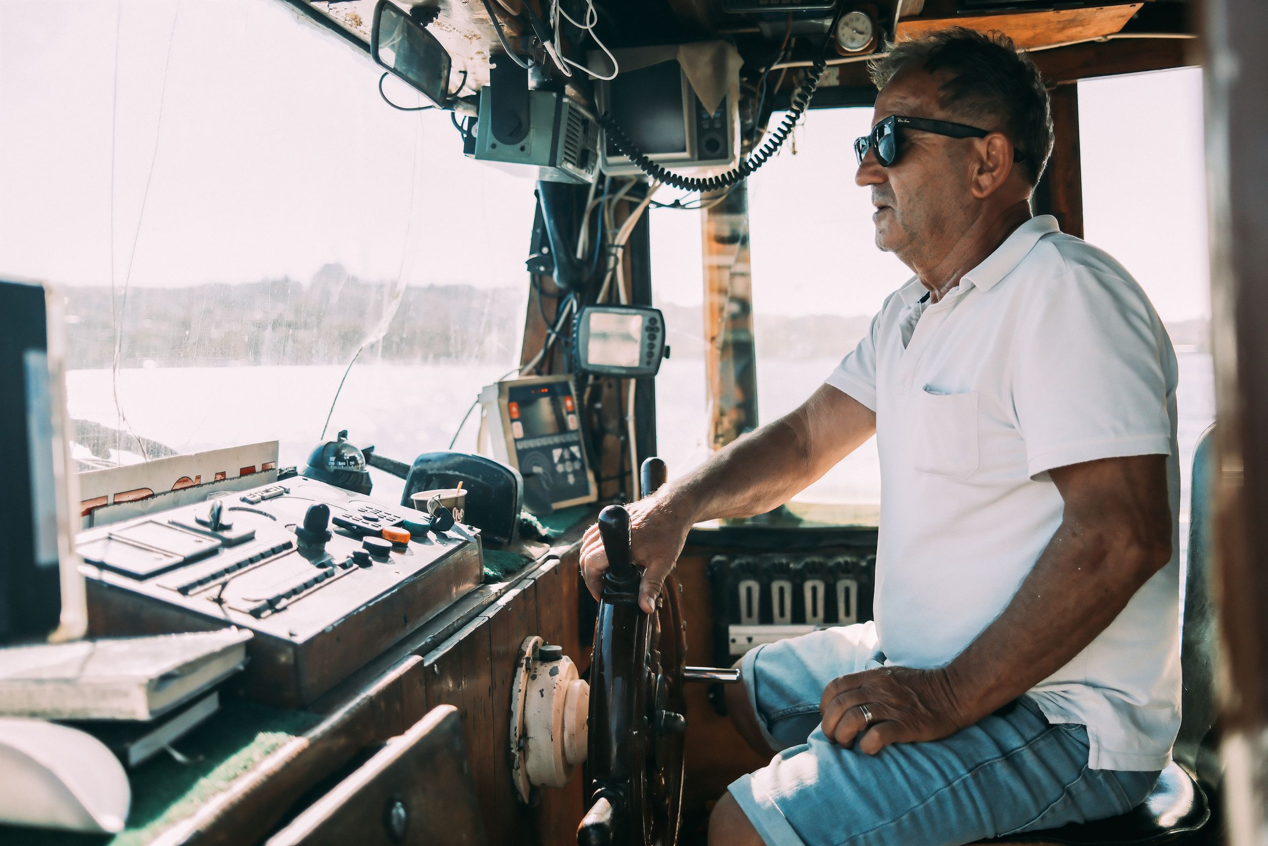 A veteran captain at the helm sharing a laugh with guests aboard a charter cruise