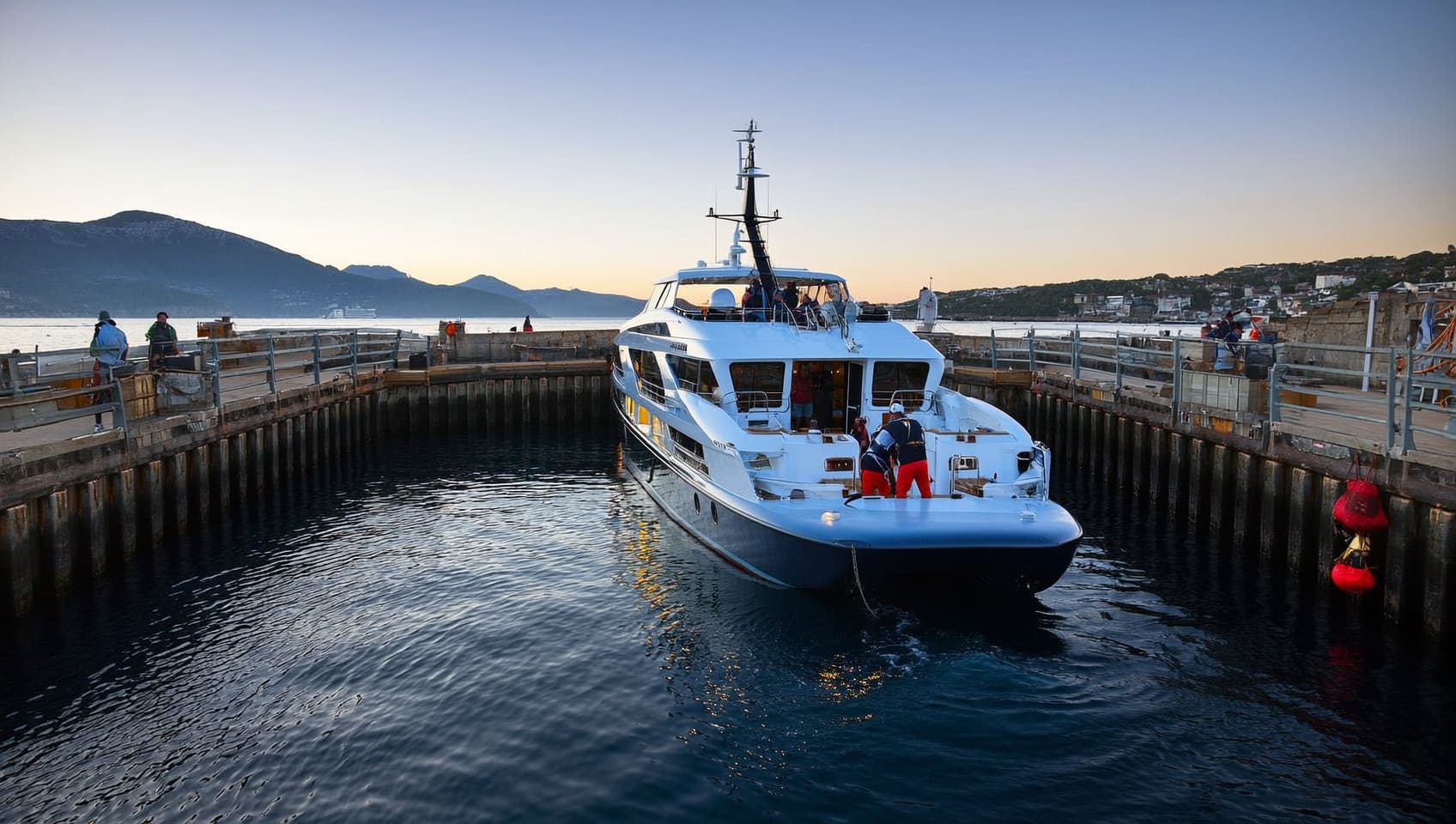 Crew guiding a JULY yacht alongside the dock at dusk